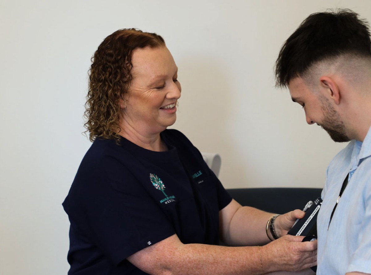 A nurse checks a patient's blood pressure, both smiling