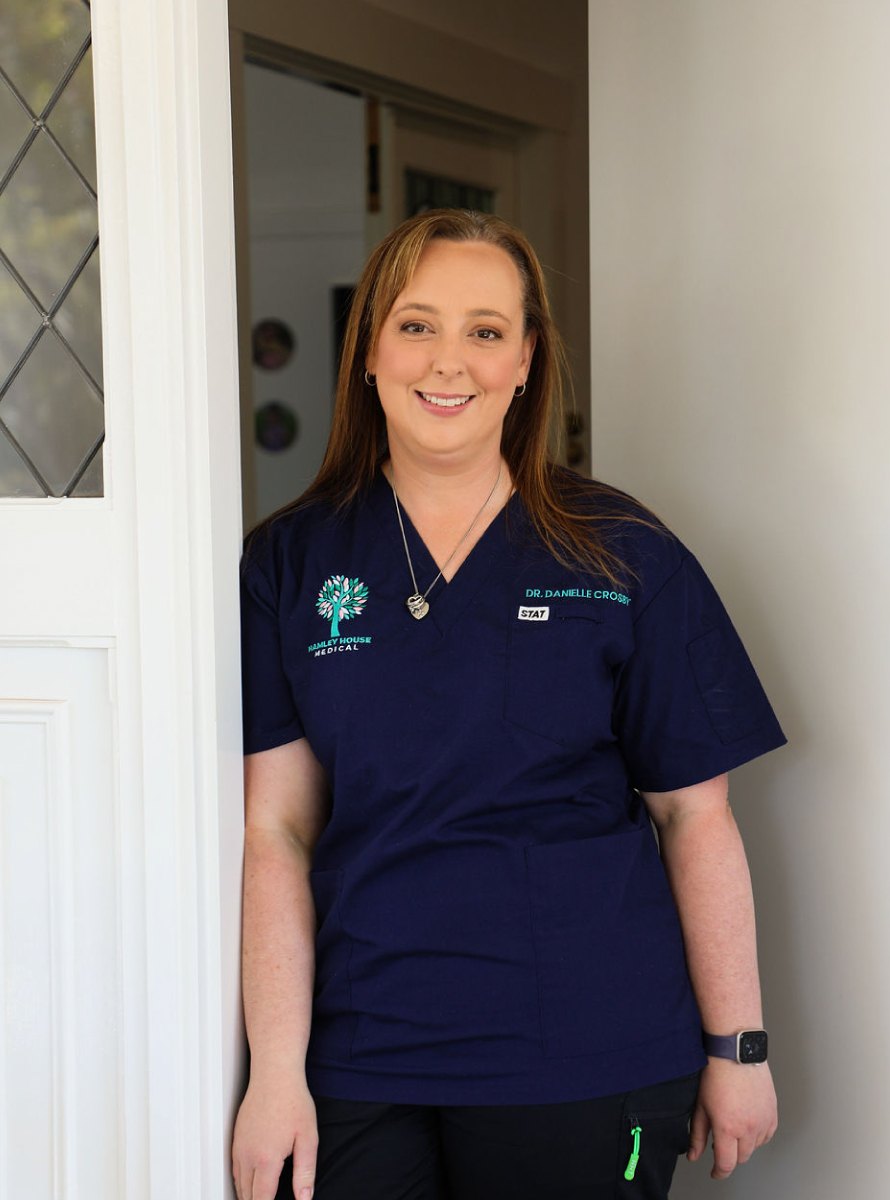 Dr Danielle Crosby standing in a doorway at the clinic, in navy Hamley House scrubs